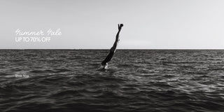 Black-and-white editorial image of a woman diving into the ocean for the Larroudé Summer Sale campaign.