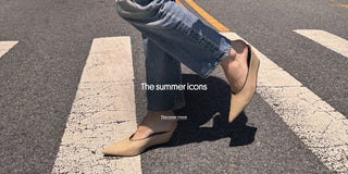 Person wearing blue jeans and beige pointed-toe flats walking across a crosswalk. The homepage banner features the text “The summer icons” and a “Discover more” call-to-action.