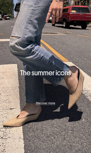 Person wearing blue jeans and beige pointed-toe flats walking across a crosswalk. The homepage banner features the text “The summer icons” and a “Discover more” call-to-action.