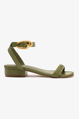 A seaweed green flat sandal with an adjustable ankle strap and golden hardware, featuring a closed round toe and a flat leather sole.